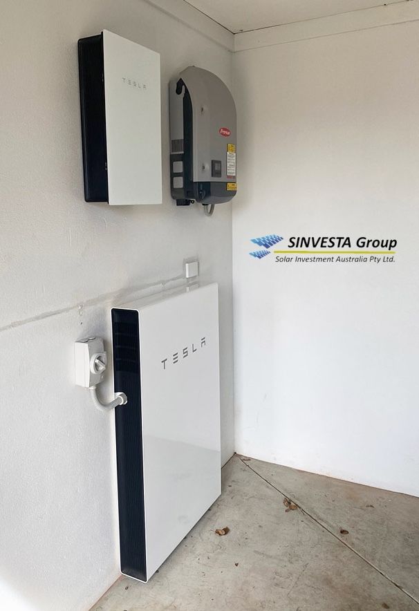 Two Tesla Powerwall units and a Fronius inverter wall-mounted in a garage by Sinvesta Group.