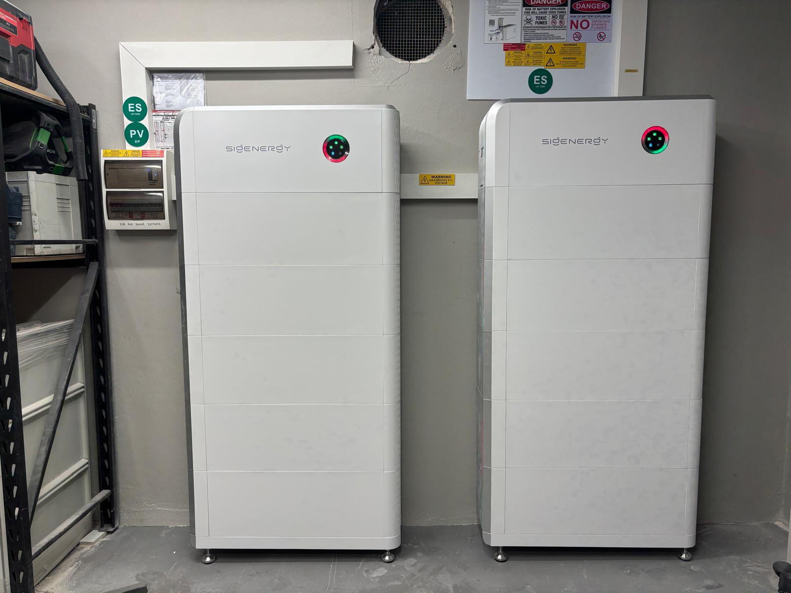 Two Sigenergy SigenStor battery stacks side by side in a garage, next to the switchboard.