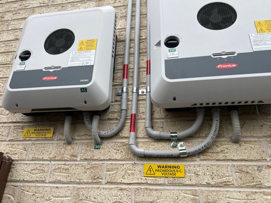 A pair of Fronius inverters installed with matched conduit runs.