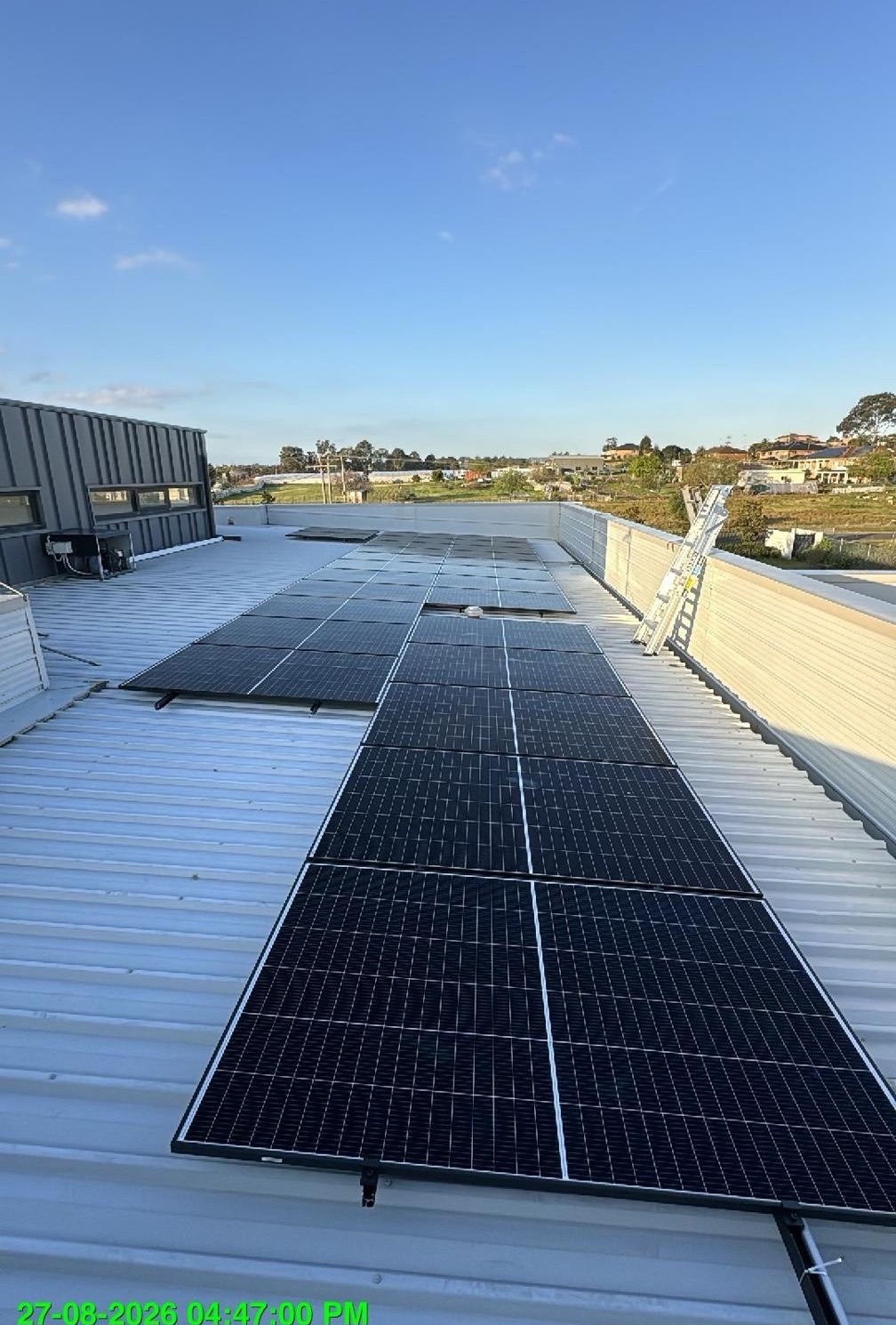 Solar array on a metal-deck roof behind a parapet wall.